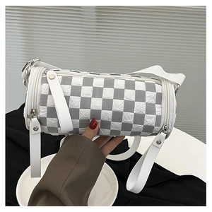 Close-up of grey checkerboard cylinder bag with wide shoulder strap and silver hardware