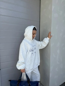 Λεπτομέρεια από γκρι oversized φούτερ με κουκούλα και τύπωμα UNITED COLLECTION μπροστά