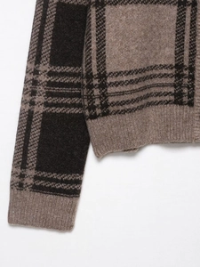 Detailed view of plaid knit pattern and ribbed cuffs on the brown check cardigan
