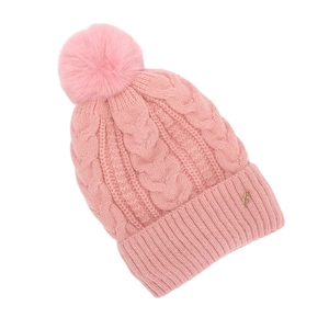 Détail du bonnet en maille rose montrant la texture torsadée et le pompon soyeux