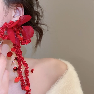 Macro detail of red fabric flower earrings with sparkling sequins and long tassels