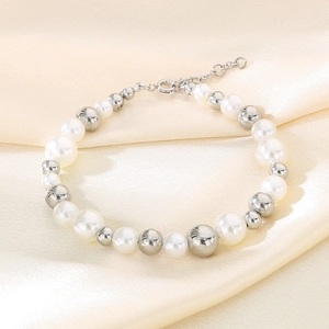 Détail du bracelet en perles d'eau douce blanches et billes d'argent sur du tissu de soie