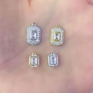 Detail of silver and gold pendants with cubic zirconia held in hand for jewelry size check