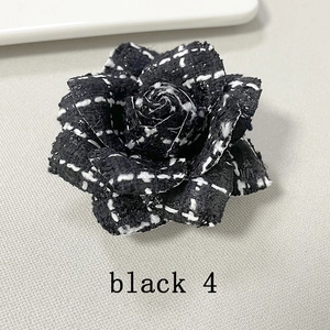 Close-up of black houndstooth tweed camellia flower brooch with intricate stitching detail