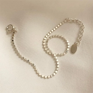 Macro shot of silver ball chain anklet with extension link and oval charm detail