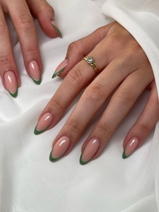 Macro detail of almond-shaped press-on nails with nude base and green French tips finish