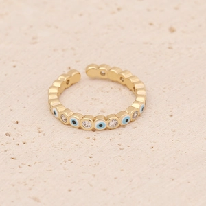 Detail of gold evil eye ring with blue and white zircon stones on stone background
