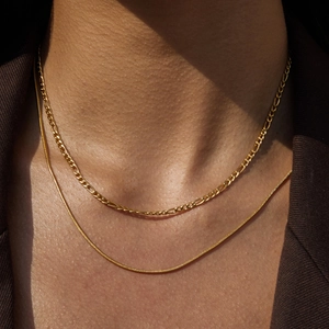 Close-up of double-layer golden Figaro and snake chain necklaces made of 18K titanium steel