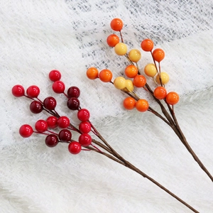 Detail of faux red and orange holly berries on stems for festive vase decoration