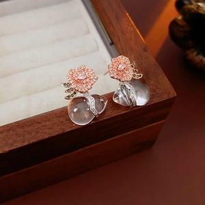 Detail of rose gold flower earrings with small diamonds and clear teardrop gemstone
