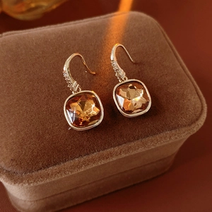 Gros plan sur boucles d'oreilles dorées avec gemme ambre sur boîte velours