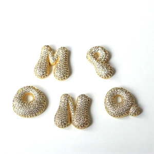 Close-up of gold-plated bubble letter charms M P O N Q with pavé cubic zirconia