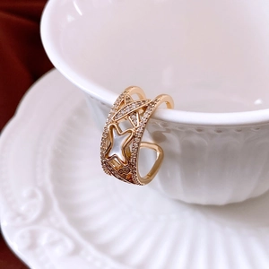 Detail of gold zircon cross open ring with star-shaped white shell inlay and sleek finish