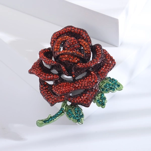 Close-up of a luxury rose brooch with deep red petals and sparkling green leaves