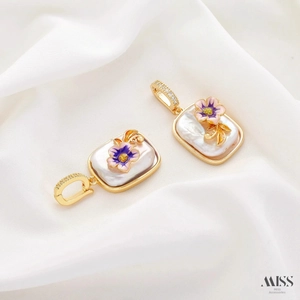Detailed macro of gold flower pendant featuring purple enamel petals and a natural pearl inlay