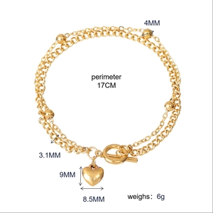 Detailed view of gold stainless steel double chain bracelet with heart charm and OT buckle
