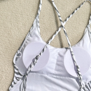 Detail of zebra print straps and built-in round pads on white backless swimsuit