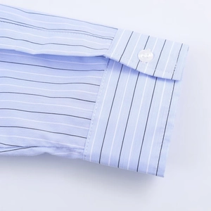 Close-up of sleeve cuff on light blue striped shirt showing fabric texture and button
