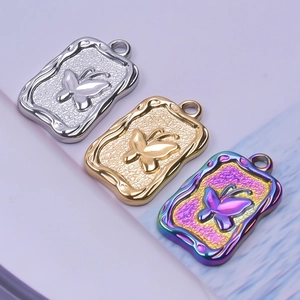 Detailed view of butterfly embossed rectangular pendants in gold, silver, and rainbow steel