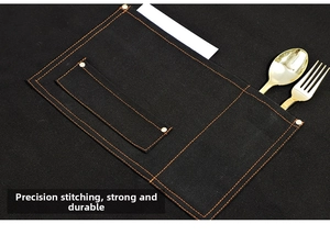 Detail of heavy-duty canvas apron with orange contrast stitching and metal rivet pockets