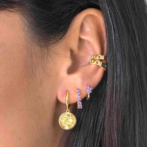 Golden geometric star and flower hoop earrings with purple crystals on female model
