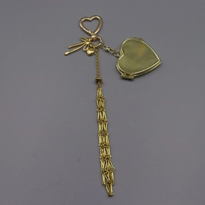 Detail of a golden heart photo frame keychain with a long metallic tassel pendant
