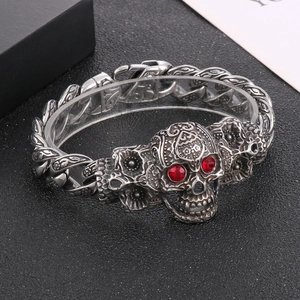 Détail d'un bracelet crâne punk avec motifs floraux vintage et yeux en cristal rouge