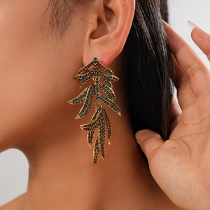 Détail de boucles d'oreilles vintage en forme de feuille dorée avec strass noirs sur modèle