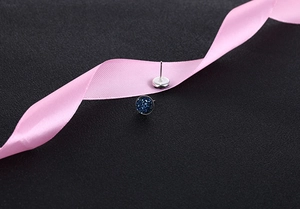Macro view of round blue crystal cluster stud earrings on elegant pink silk ribbon