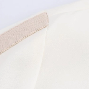 Close-up of high-quality white fabric with beige braided decorative stitching detail