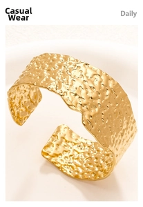 Detailed close-up of 18K gold-plated wide cuff bracelet with irregular hammered texture