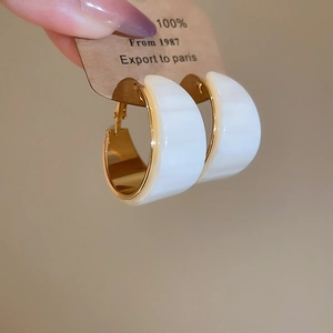 Détail des boucles d'oreilles géométriques en résine plaquée or 18 carats sur étiquette