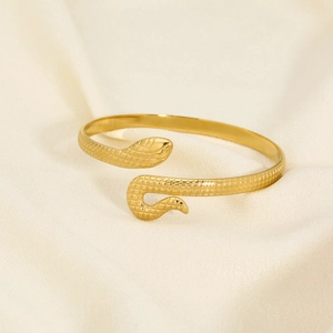 Macro detail of golden snake-shaped open bracelet with intricate scale texture