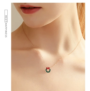 Detail of Christmas wreath pendant necklace with red bow on a gold chain