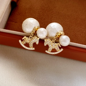 Macro shot of gold rocking horse earrings with pearls and white cubic zirconia