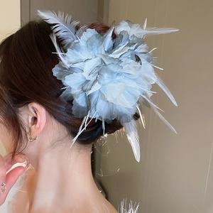 Detail einer blauen Organza-Blumen-Haarklammer mit Federn an der Model-Frisur