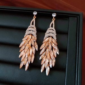Macro detail of champagne gold feather tassel earrings with crystal fringe and diamonds