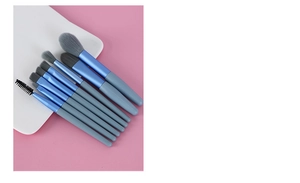 Detail of 8-piece blue portable makeup brush set with soft grey bristles on white tray