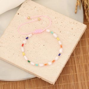 Macro shot of handmade beaded bracelet with white pearls and colorful beads on woven cord
