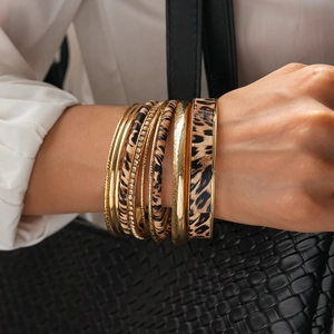 Dettaglio di bracciali rigidi dorati multistrato con stampa leopardata e cristalli