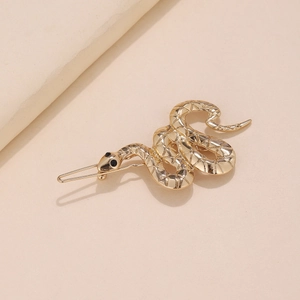 Detailed macro view of a golden snake hair clip with textured scales and black gem eyes