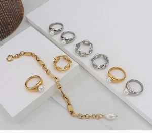 Collection of faux pearl rings and gold chain bracelets on a white marble display