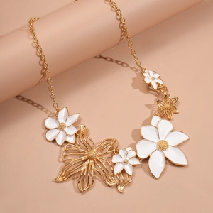 Detailed close-up of a gold floral necklace with white enamel petals and hollow metal patterns