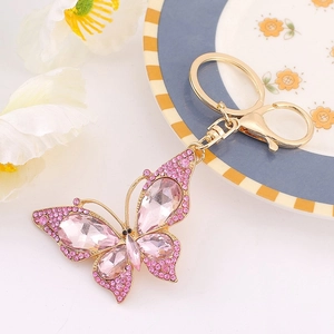 Dettaglio portachiavi a fiocco dorato con cristalli rosa su fiore bianco e piatto decorato