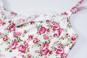 Detailed macro view of white floral dress featuring red rose pattern and delicate lace trim
