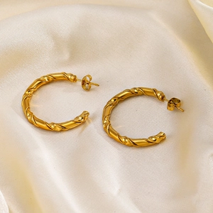 Minimalist C-shaped 18K gold plated twisted hoop earrings on beige silk fabric