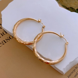 Gros plan de boucles d'oreilles dorées géométriques avec détails de texture martelée