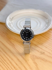 Detailed macro view of the silver metal strap watch with crystal markers on a black dial