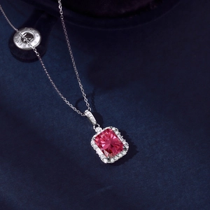 Macro detail of silver necklace featuring a rectangular pink zircon stone on blue velvet