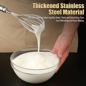 Manual stainless steel whisk lifting fresh white cream from a glass bowl in a kitchen
